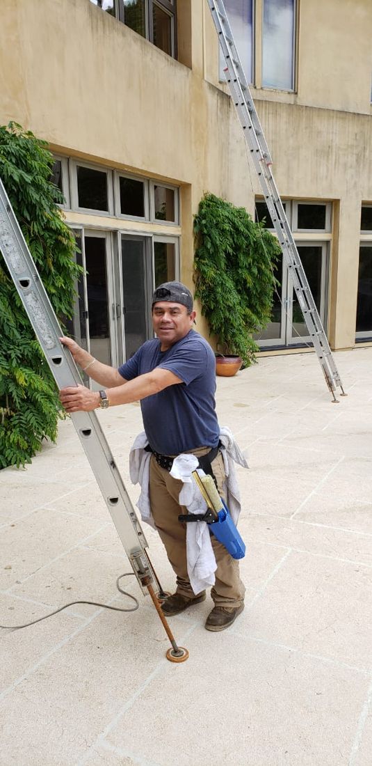 Clean and Sparkle window cleaner smiling beside his ladder on the job